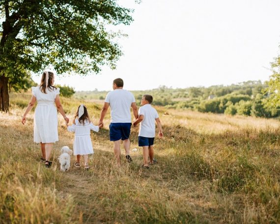 A family walking through a field with a dog