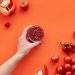 A vibrant display of red fruits and vegetables on a red background with space for text.